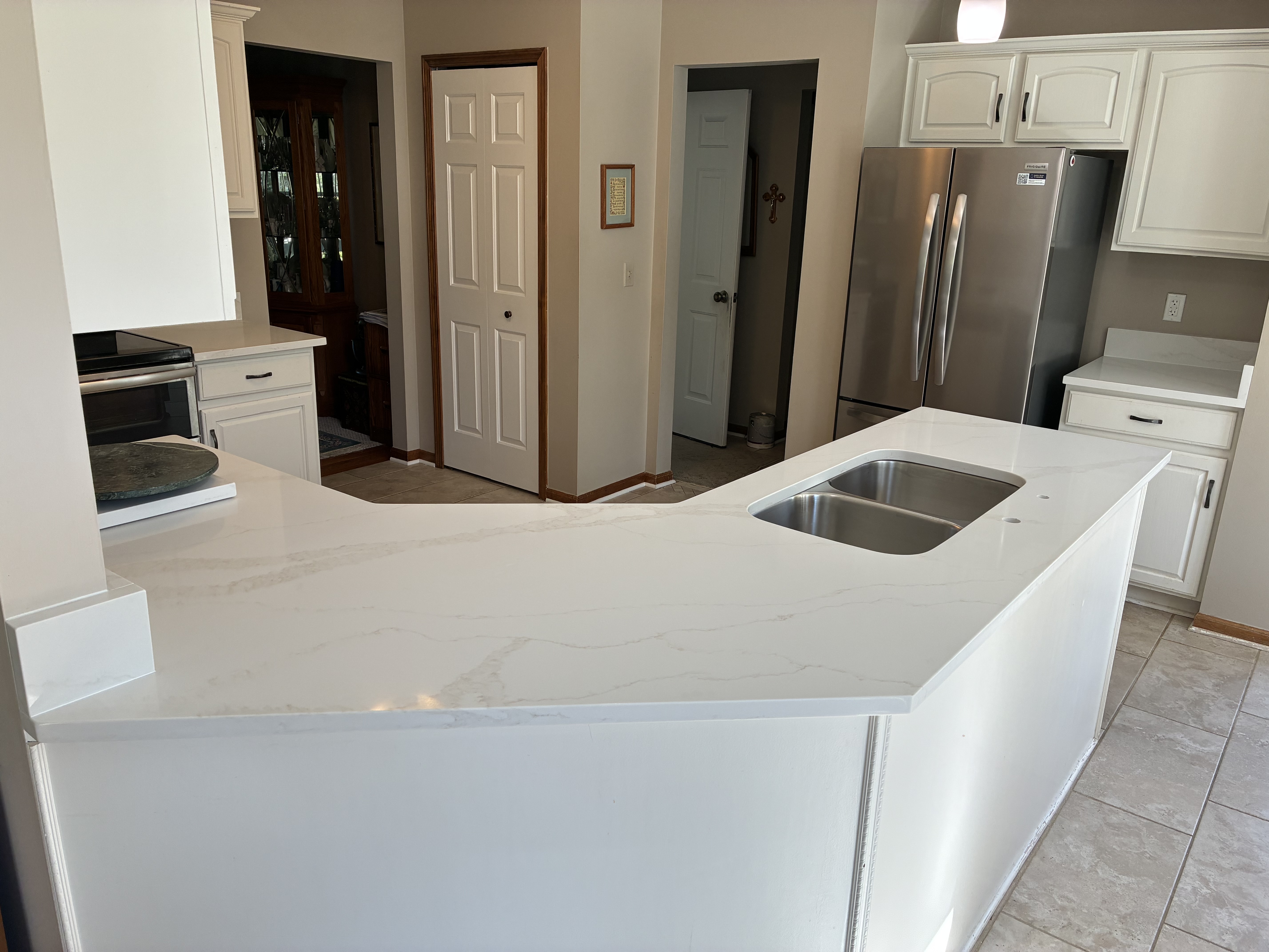 U-shaped white quartz kitchen with grey veining and double-bowl sink