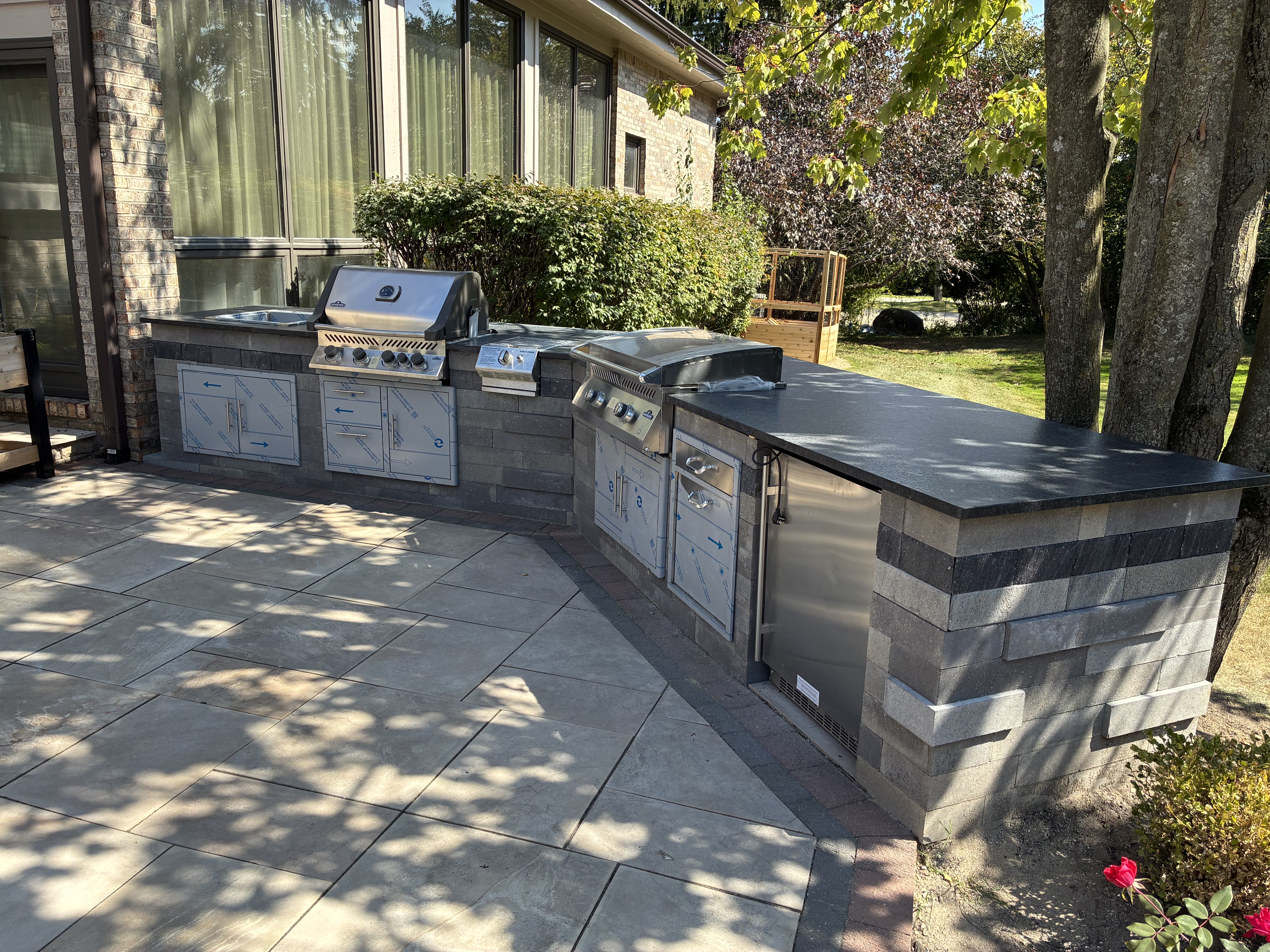 Outdoor kitchen with built-in grill, sink, and stone masonry base