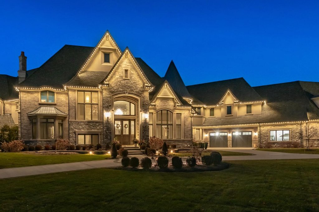 Elegant estate home with warm white Gemstone Lights holiday display at dusk