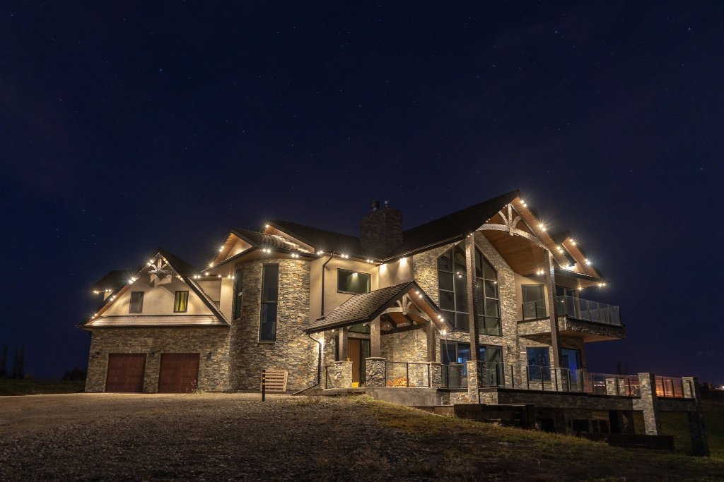 Grand stone and timber custom home with warm white Gemstone Lights under starry night sky