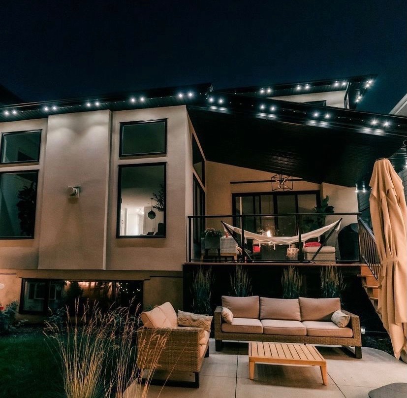 Modern home outdoor living space with Gemstone Lights on roofline and deck pergola at night