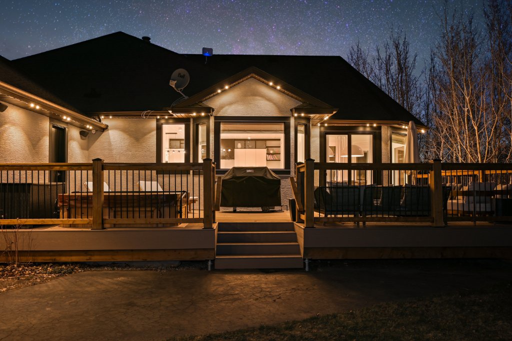 Back deck and covered porch with warm Gemstone Lights under a starry night sky