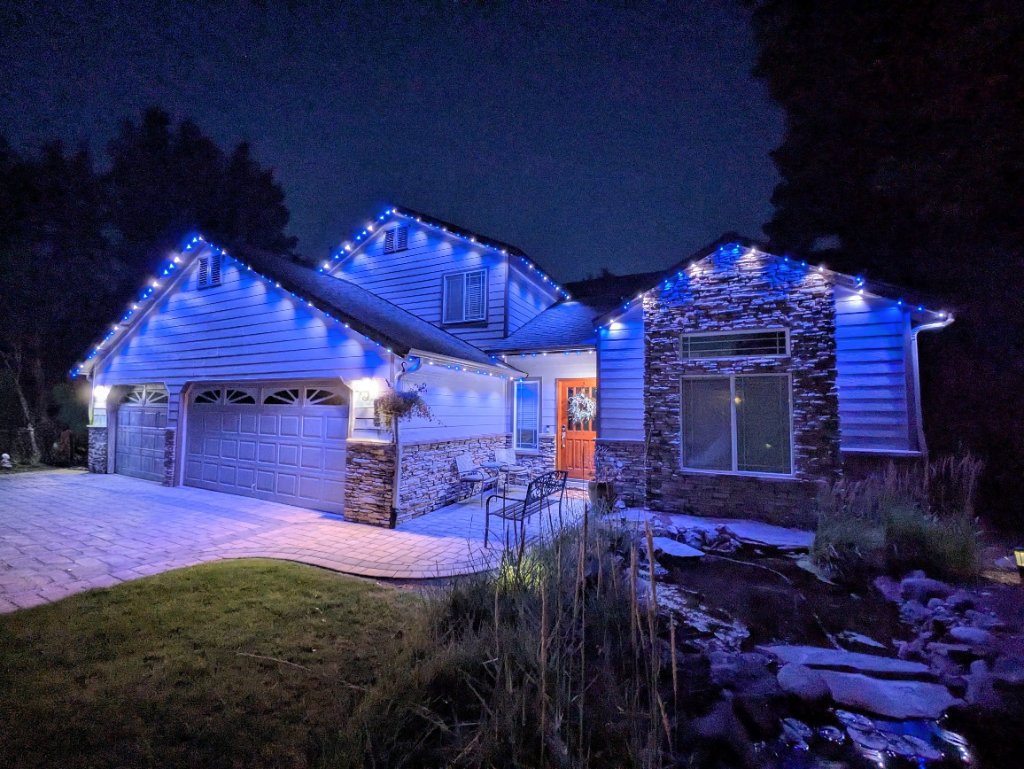 Multi-level home with vibrant blue Gemstone Lights roofline display at night in Redmond, Oregon