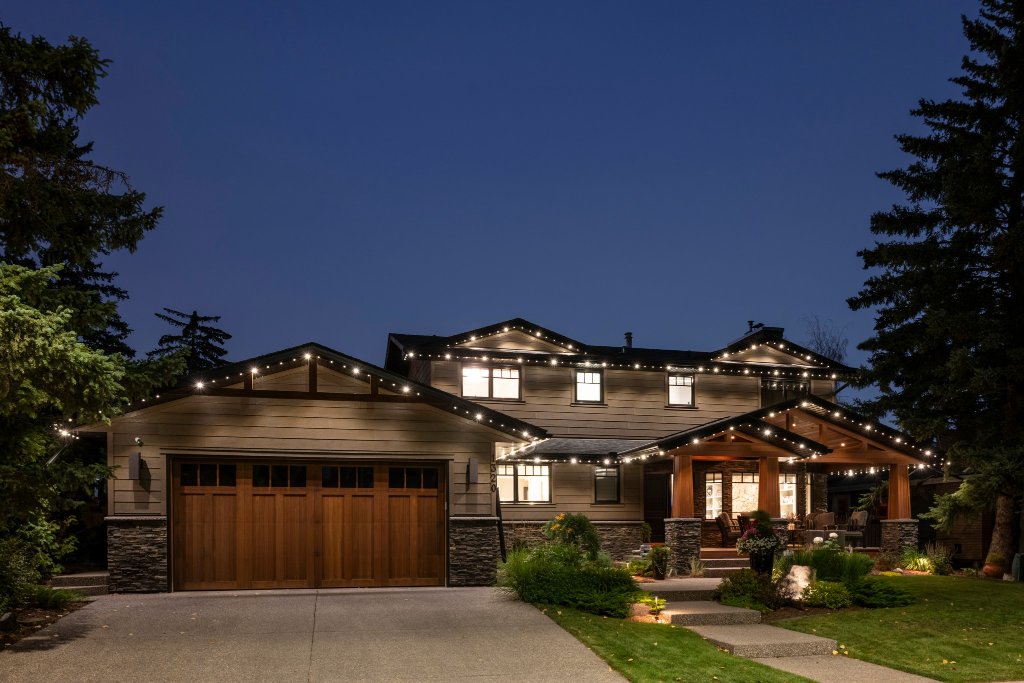 Full roofline Gemstone Lights installation on craftsman home with stone accents at dusk