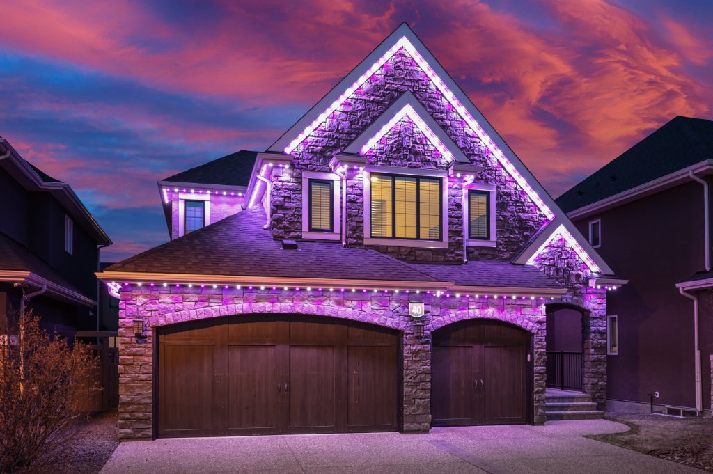 Stone home with vibrant purple Gemstone Lights roofline display at sunset