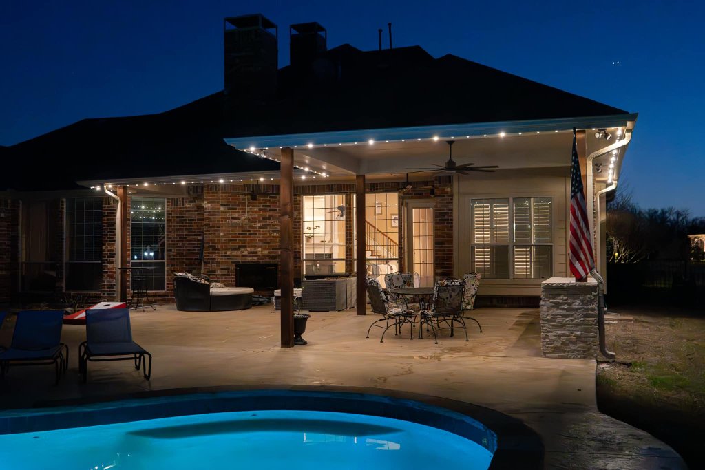 Covered patio and pool area with Gemstone Lights roofline accent lighting at dusk