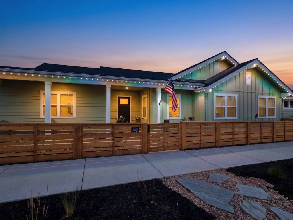 Sage-green home with patriotic red, white, and blue Gemstone Lights roofline display at twilight in Bend, Oregon