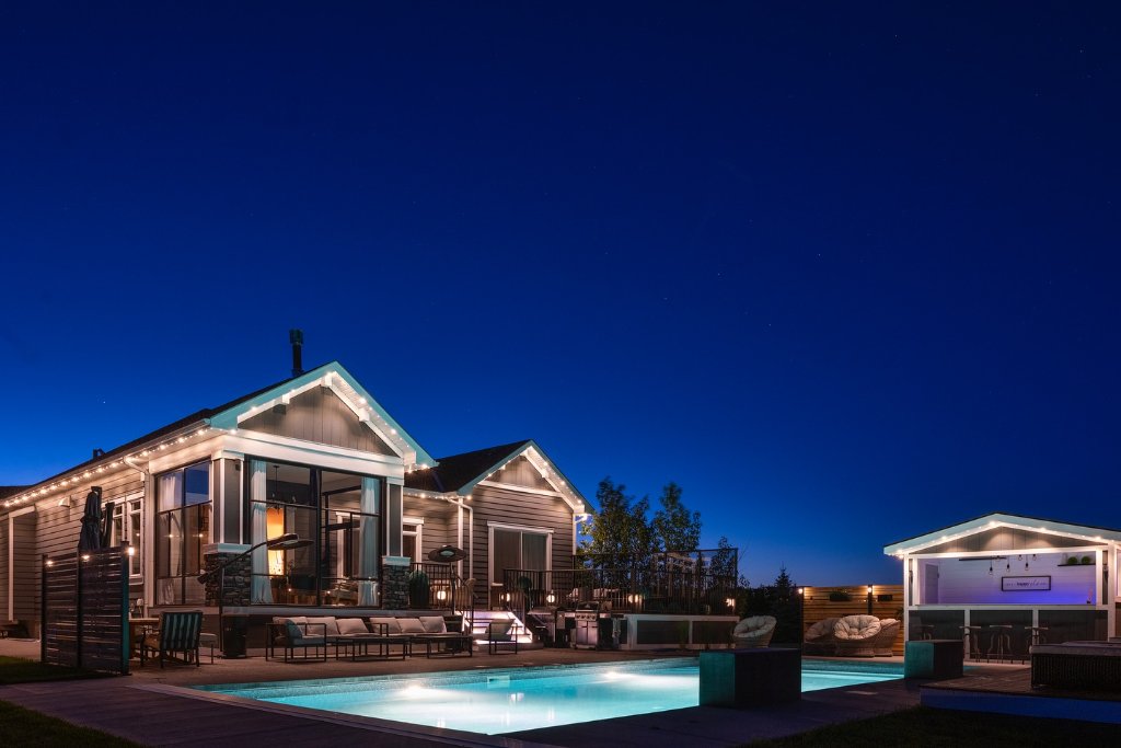 Backyard pool and patio with Gemstone Lights roofline and pool house accent lighting at night