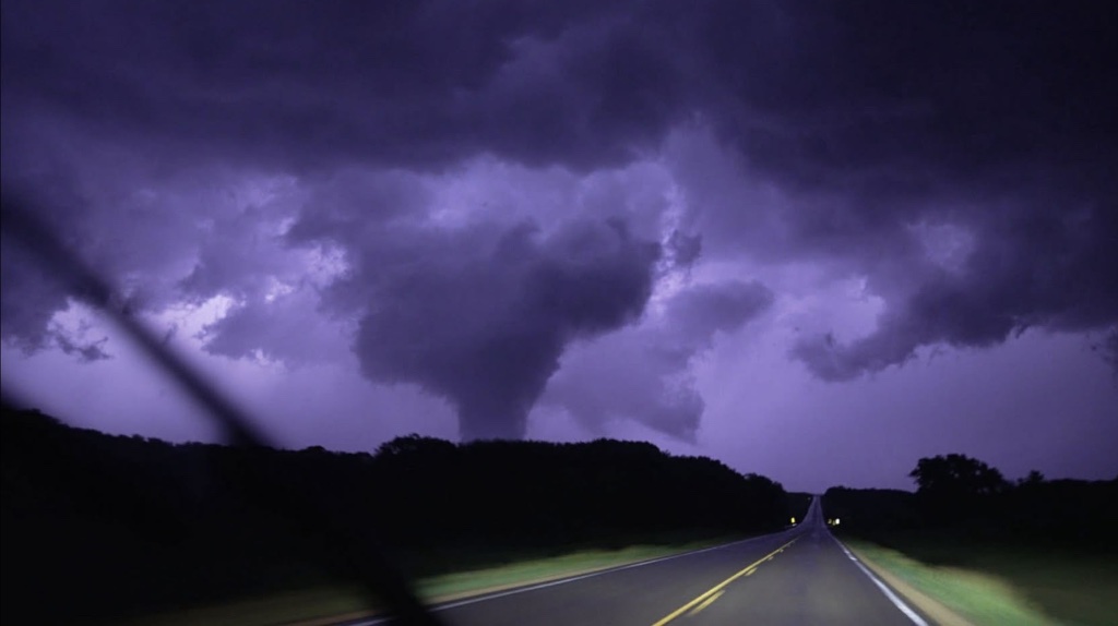 Nighttime tornado silhouetted against a purple-lit sky