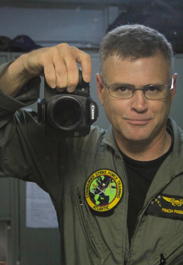 Bill 'Pinch' Paisley in flight suit holding a Canon camera