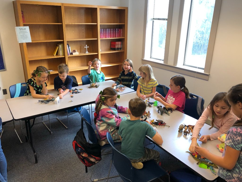 PHOTO: Homeschool outreach — children observing frogs with UV flashlights at night, or a group examining specimens at a table.