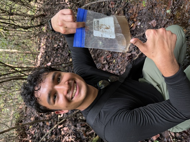 A student holds up a stream sample collected during a field activity.