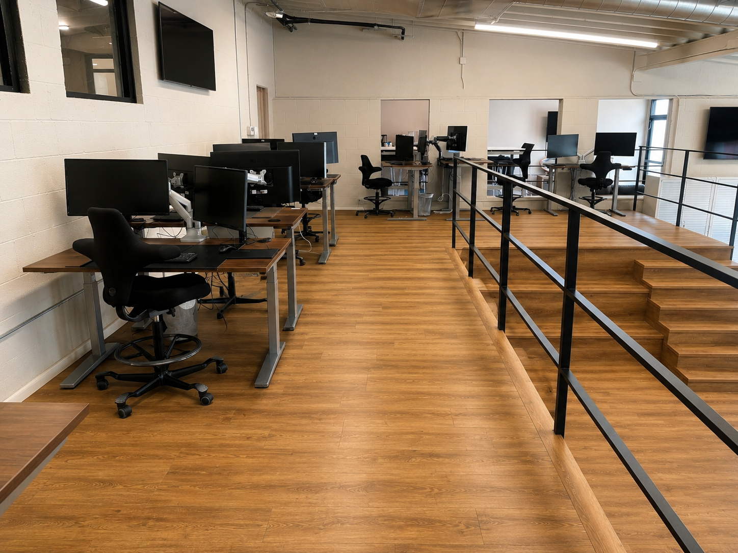 Open work floor at The Visionary — rows of dual-monitor stand-up desks on a raised mezzanine