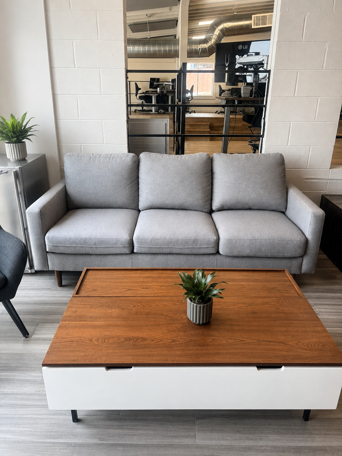 3rd-floor collaboration lounge at The Visionary — grey sofa, coffee table, and open partition
