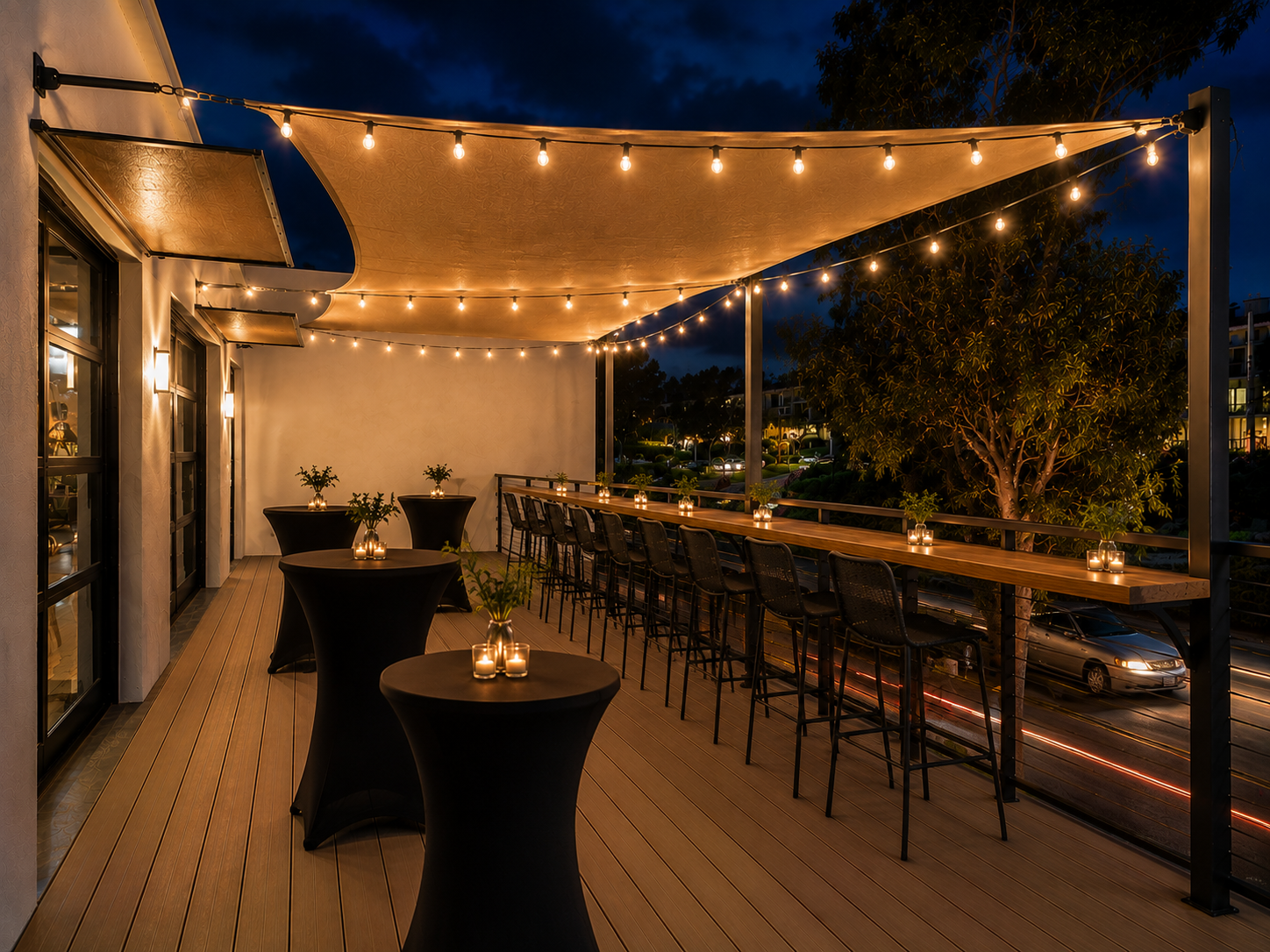 The back deck at The Visionary at night — cocktail tables, bar seating, and string lights under the awning