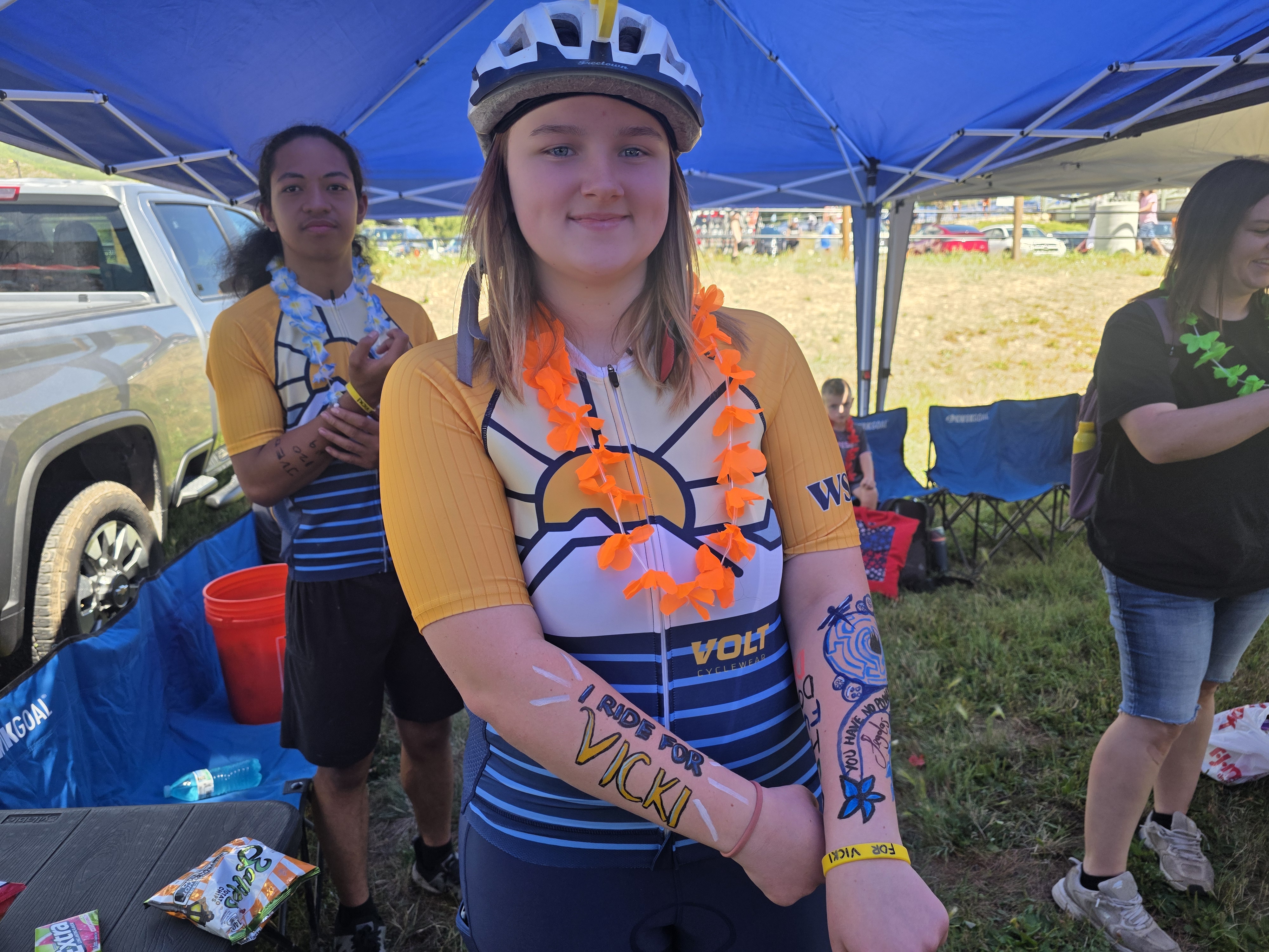 Rider under the team canopy with "I Ride For Vicki" painted on her arms