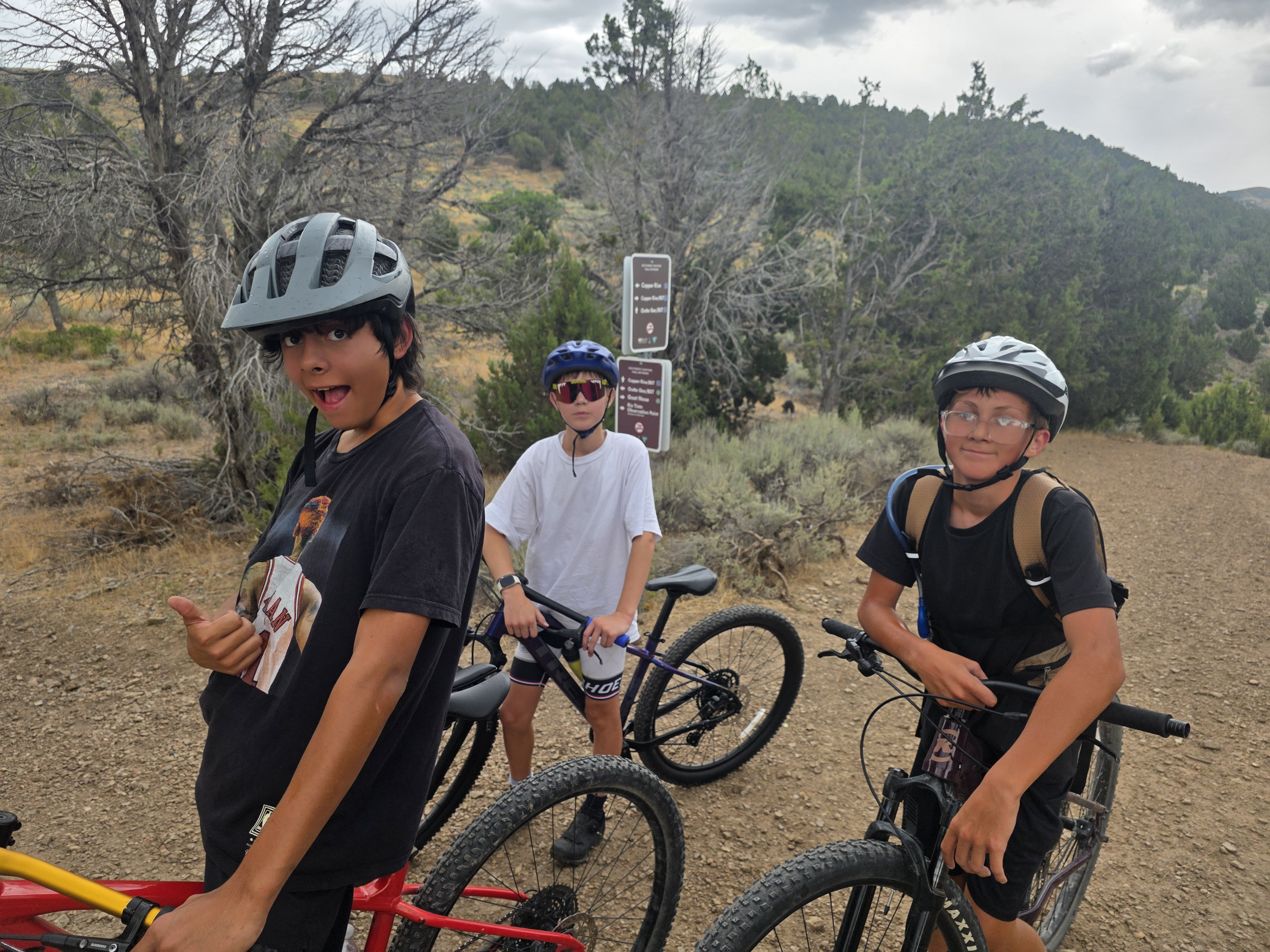 Three riders posing with bikes on a dirt trail