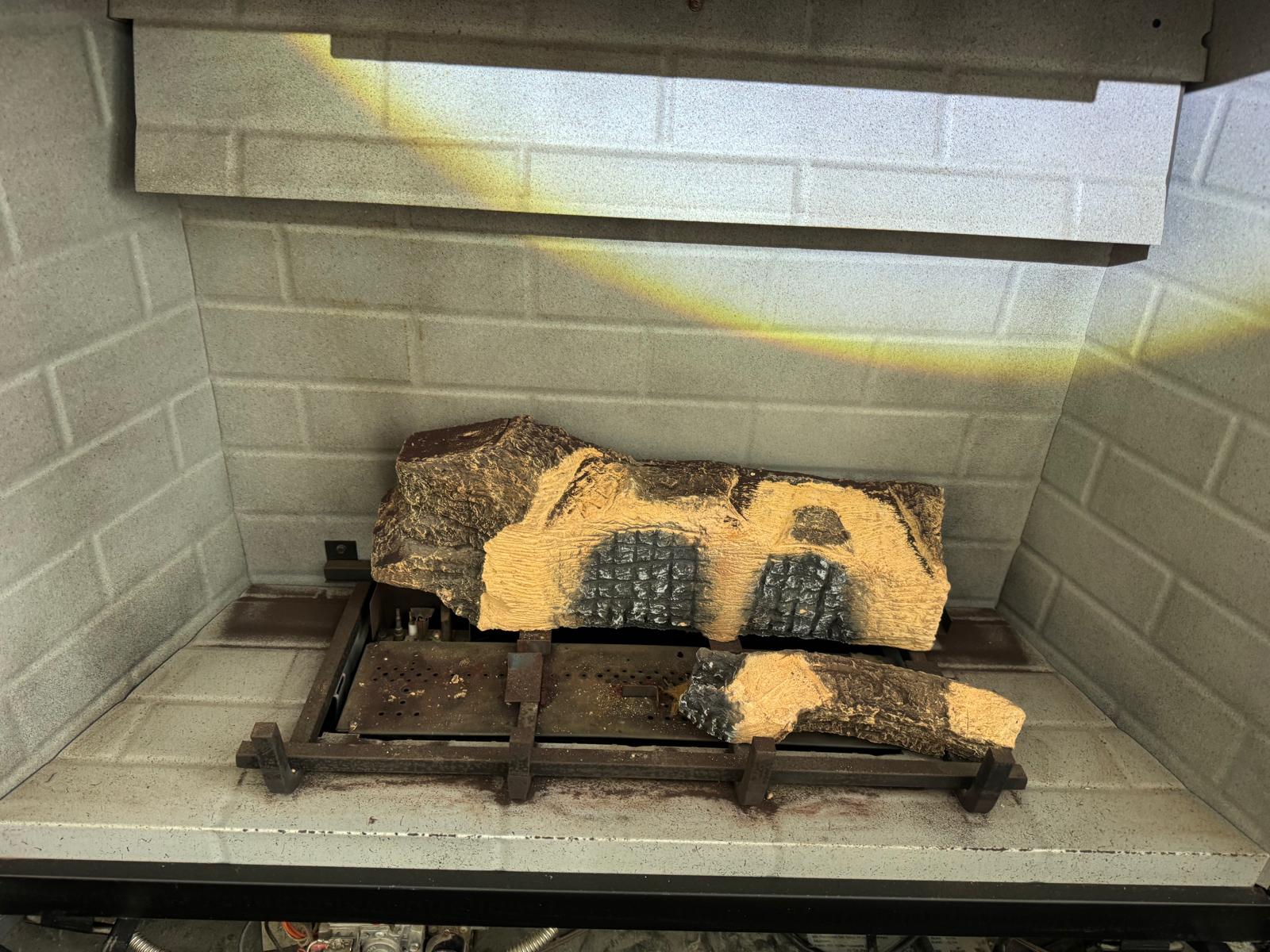Ceramic gas logs arranged on burner grate inside fireplace firebox
