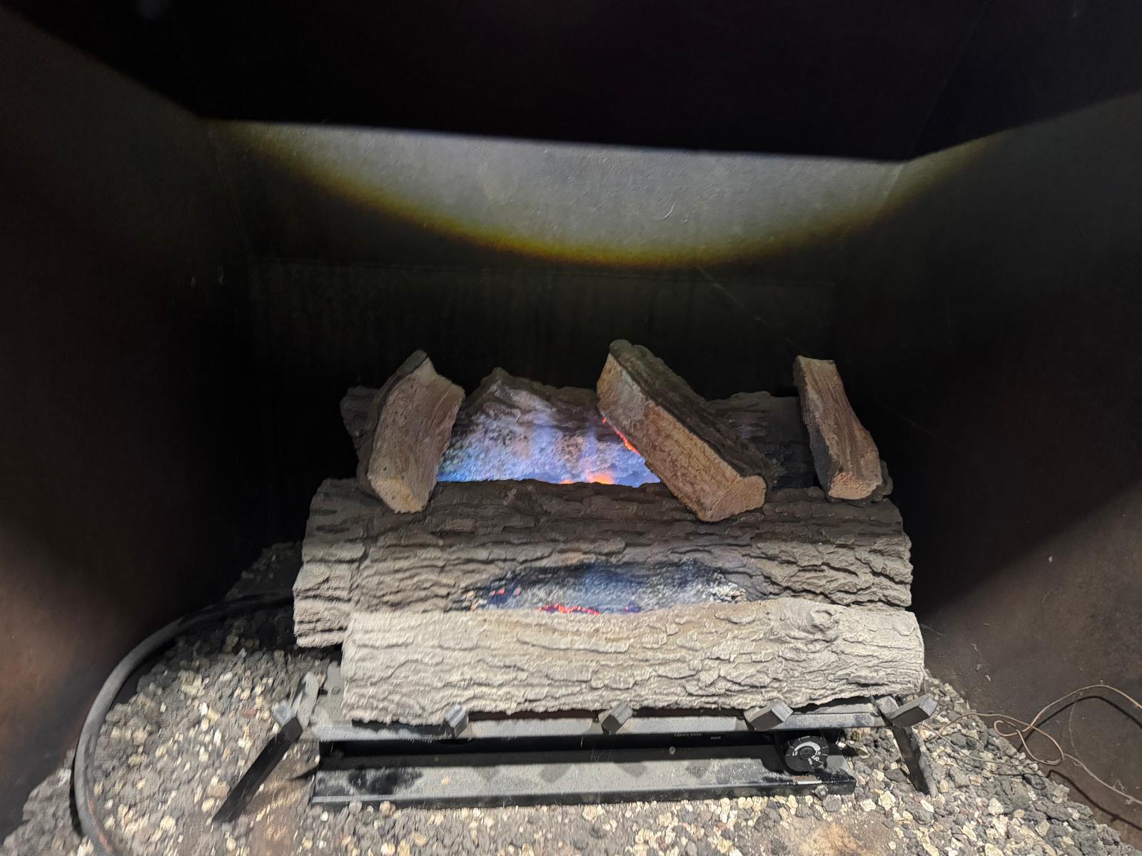 Gas fireplace with bright orange flames burning in a brick hearth fireplace