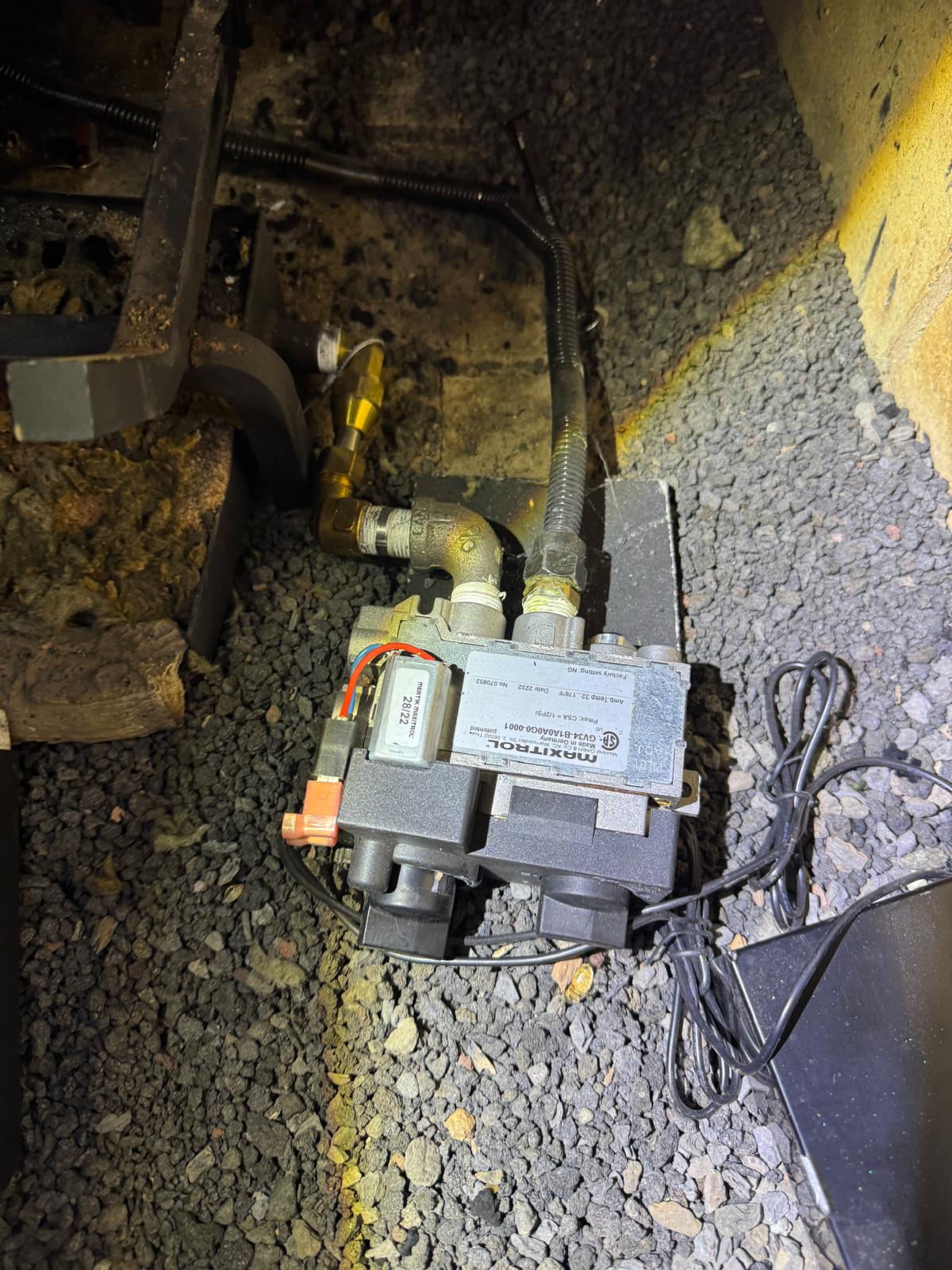 Technician hands working with gas valve parts and tools during fireplace repair