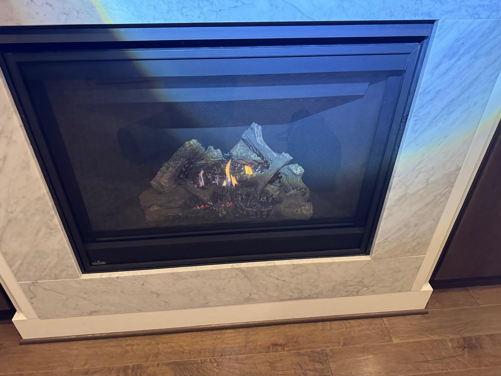 Napoleon gas fireplace with warm flames in a marble surround after servicing