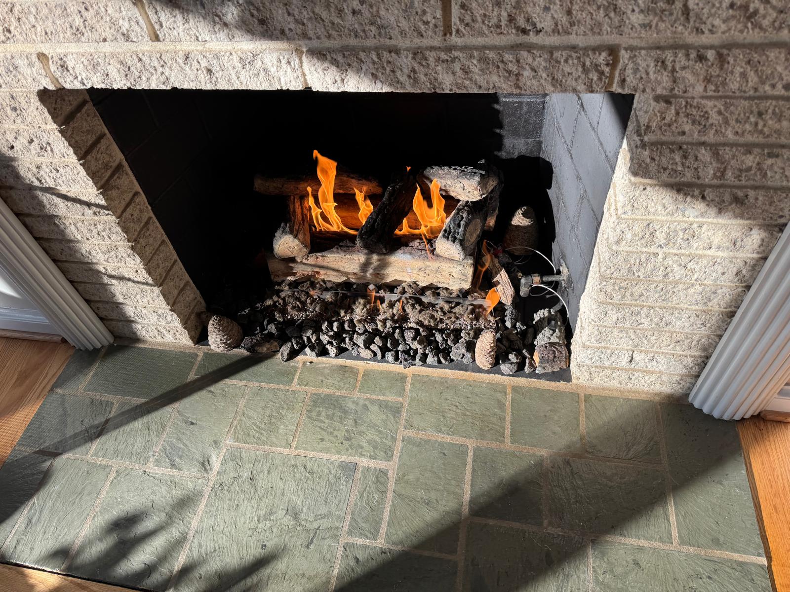 Technician hand placing ceramic gas fireplace logs into proper position