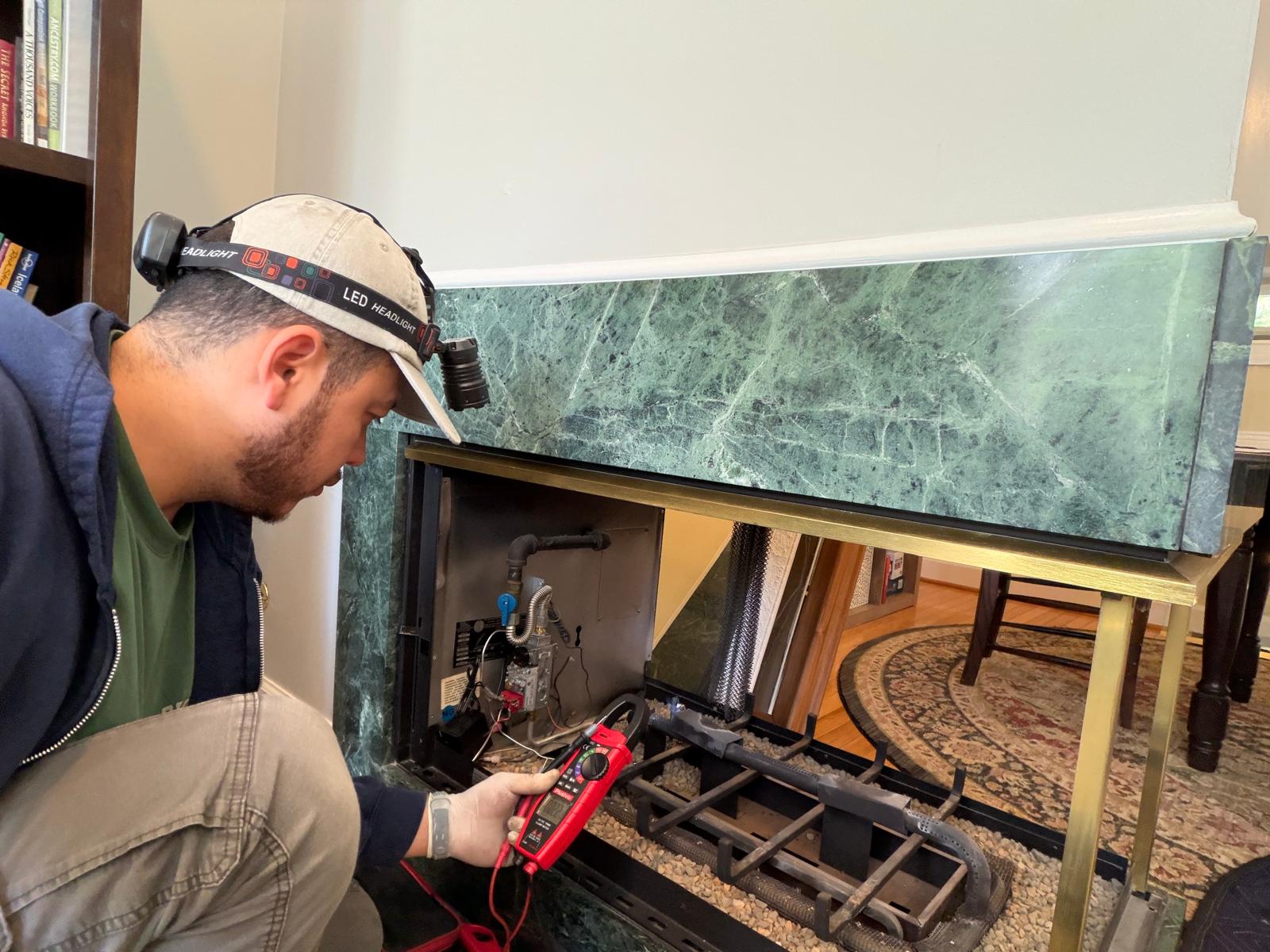 Capital Gas Fireplace technician using a multimeter to diagnose gas valve and thermocouple wiring on a marble-surround fireplace in Northern Virginia