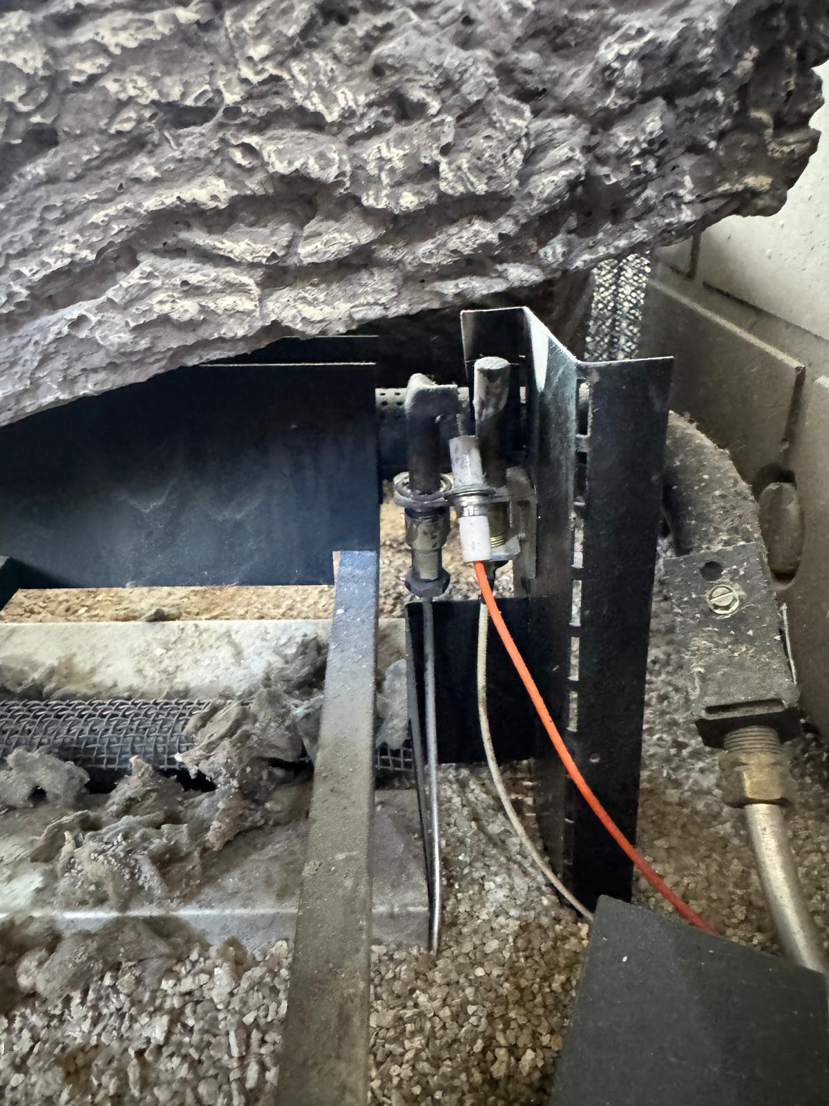Gas fireplace igniter and thermocouple wiring inside firebox during repair