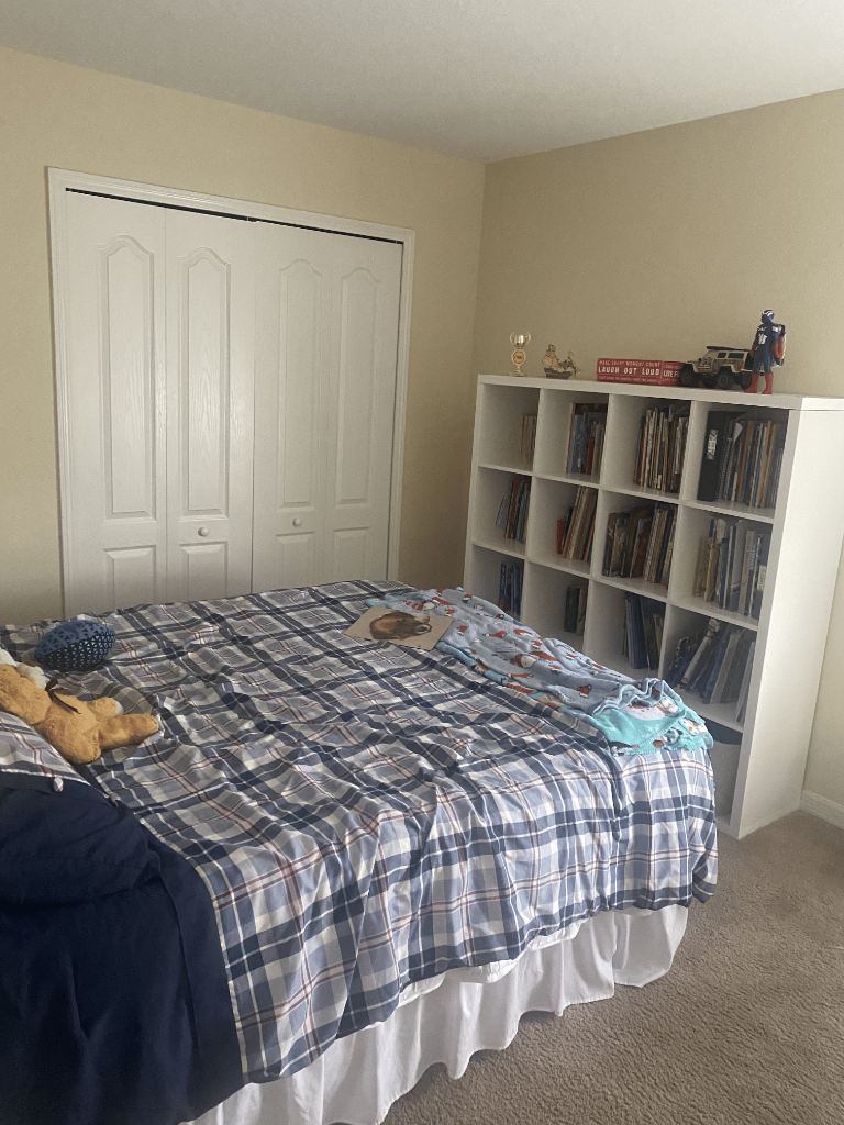 Bedroom with blue plaid comforter, white cube bookshelf, and Captain America figure