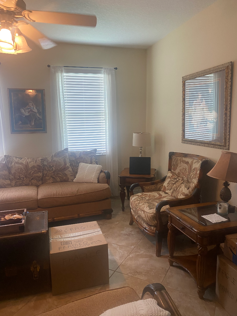 Living room with floral sofa, armchair, and framed art on beige walls