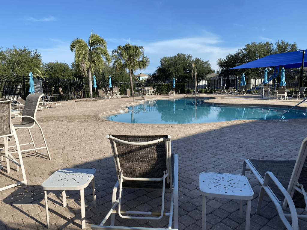 Mira Lago community pool with turquoise water, lounge chairs, and blue shade canopy