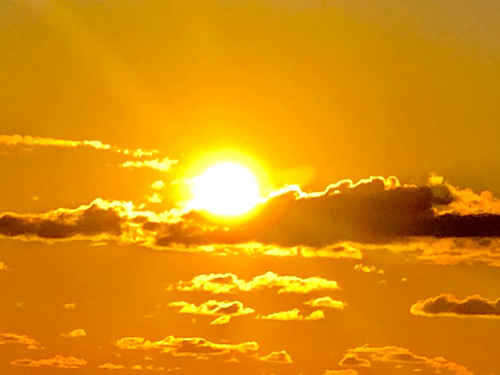 Brilliant golden sunrise glowing through a thin band of clouds