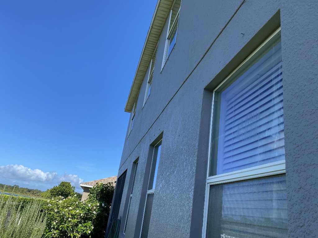 Side of the house exterior with hurricane screens and lush garden