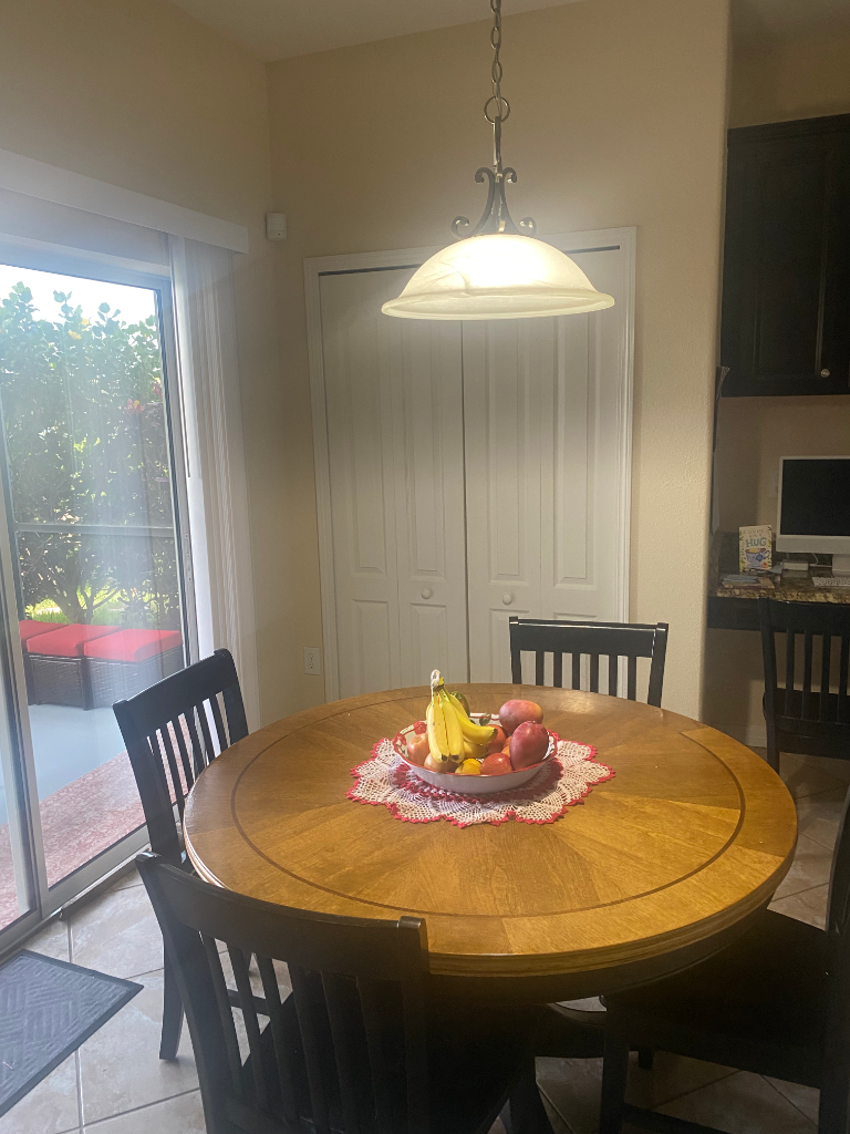 Dining nook with round wooden table, pendant light, and fruit bowl