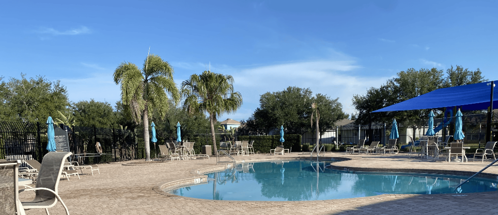 Mira Lago community pool with lounge chairs, palm trees, and clear blue water on a sunny day