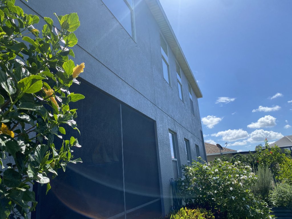 Exterior side of home with hurricane screens and clear blue sky