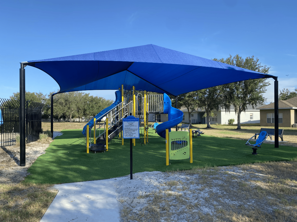 Community playground with blue slides and shade structure