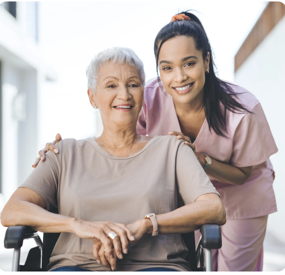 A caregiver supporting an elderly woman seated in a wheelchair