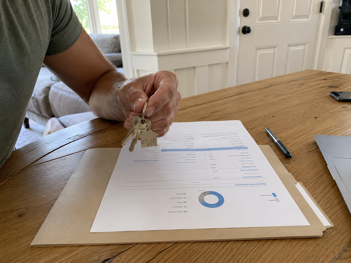 Hand met sleutels en financieel rapport op tafel