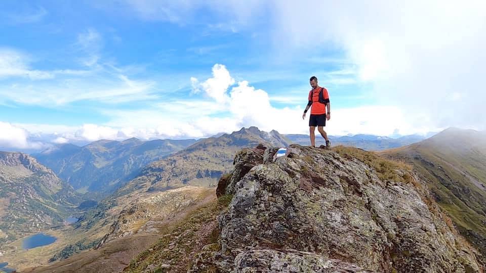 Trail runner on a mountain summit with alpine panorama