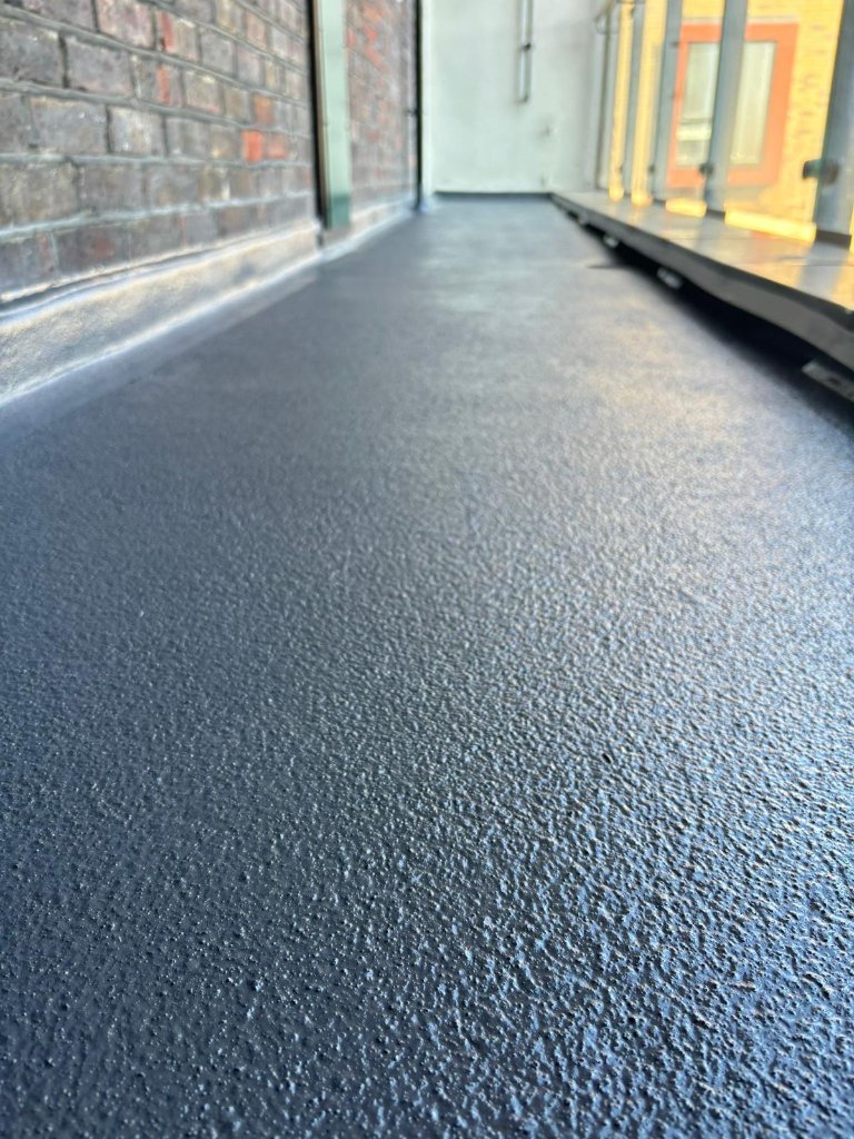 Close-up of completed spray-applied membrane surface showing textured anti-slip finish