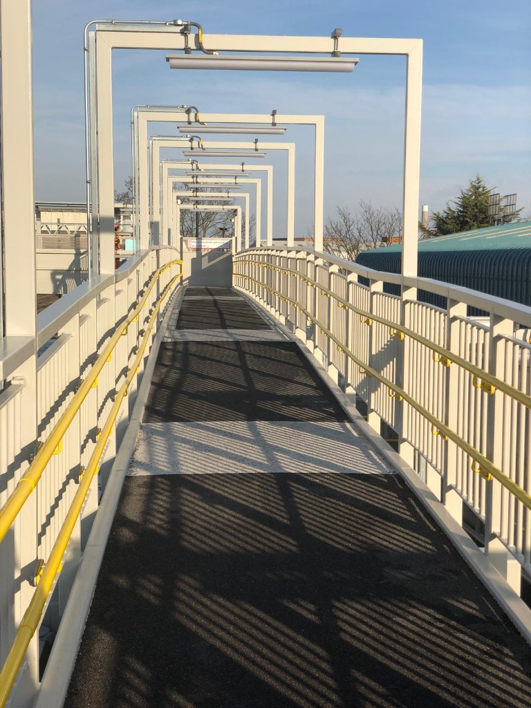 Completed industrial walkway bridge — spray-applied anti-slip membrane with safety railings