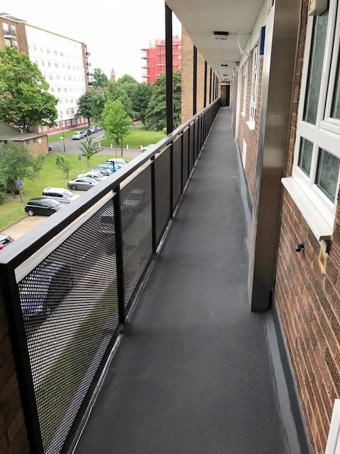 Completed waterproof walkway deck — residential balcony corridor coated in dark grey membrane