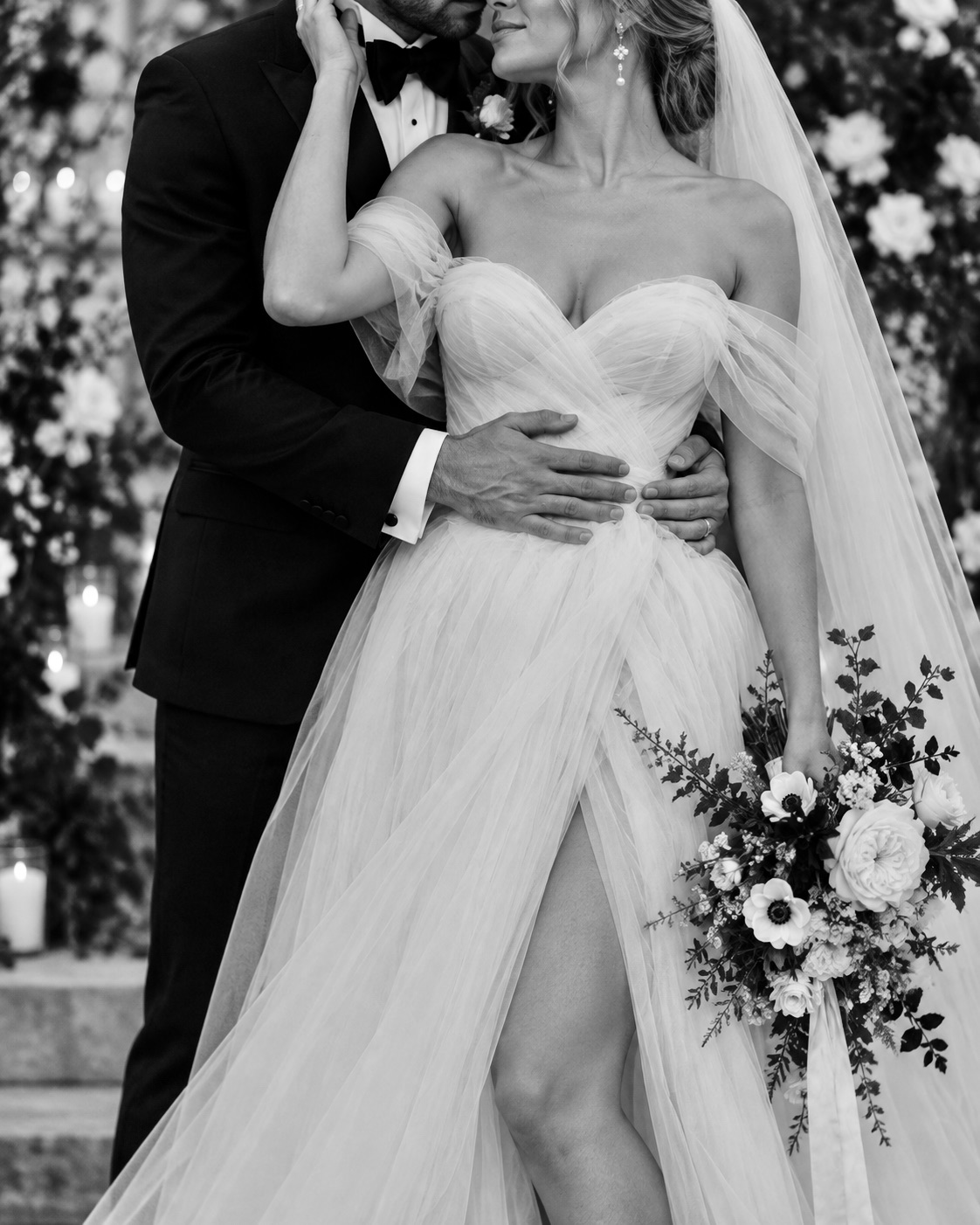 A bride and groom in an intimate embrace — editorial black-and-white portrait.