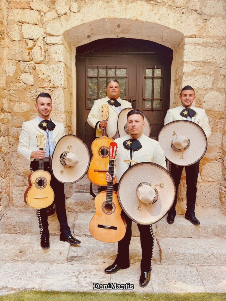 Mariachi Estrellas de Madrid posando con sombreros y guitarras en fachada de piedra