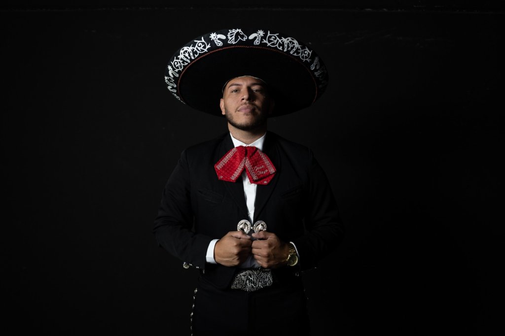 Integrante de Mariachi Estrellas Madrid con traje charro completo posando en fondo negro