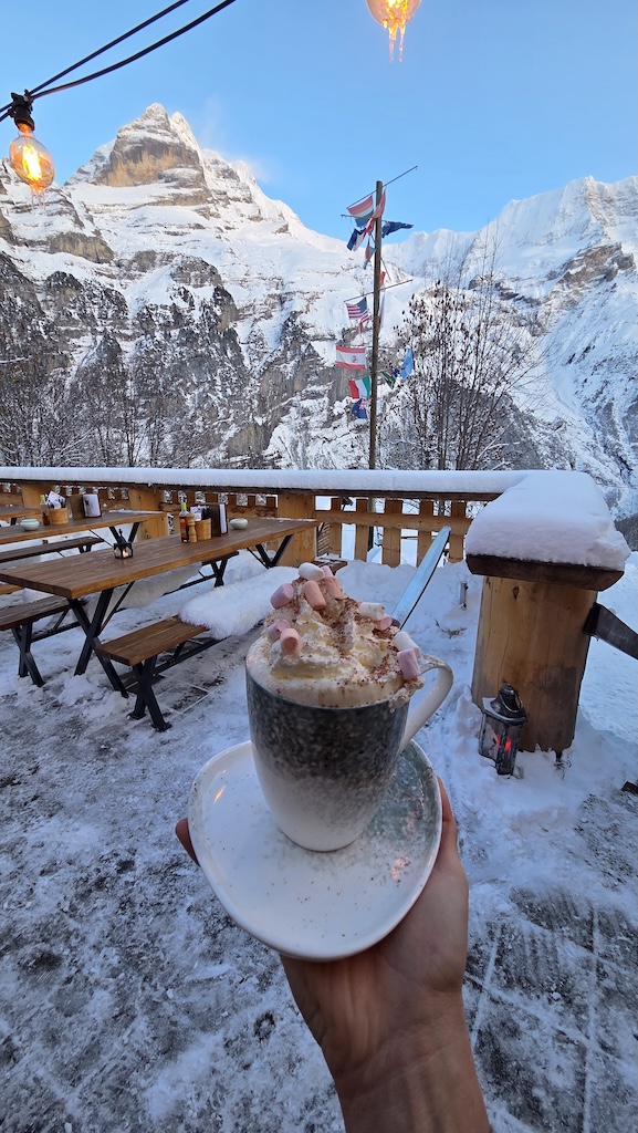 Hot chocolate with marshmallows overlooking snowy peaks