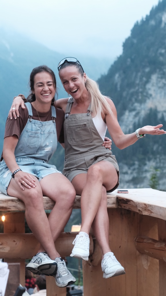 Two friends laughing on a wooden bench in the valley