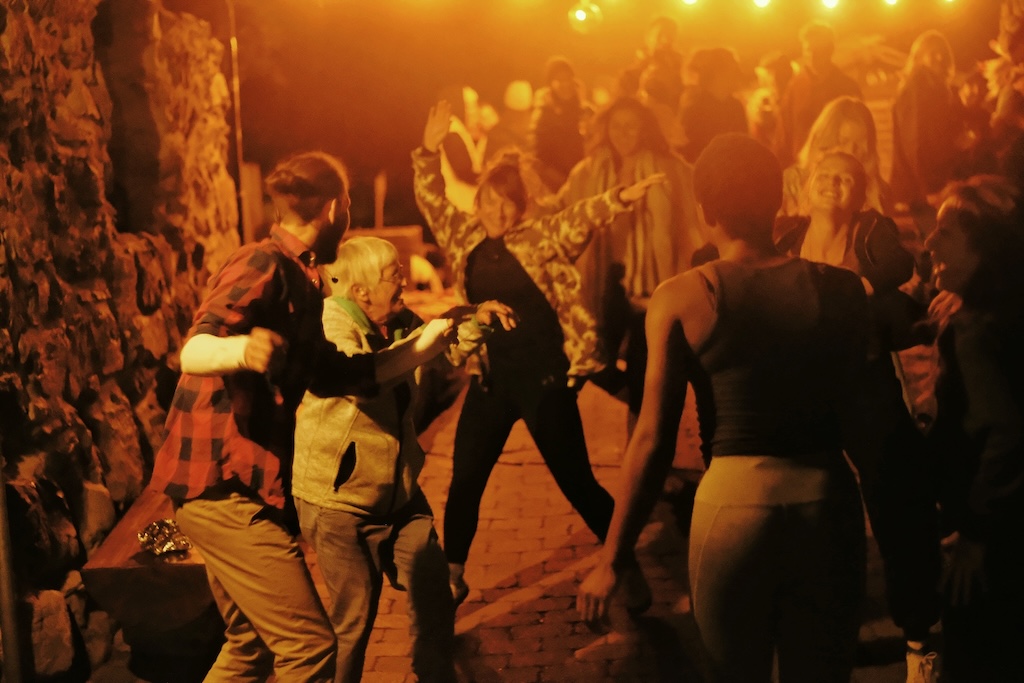 People dancing outside under warm party lights