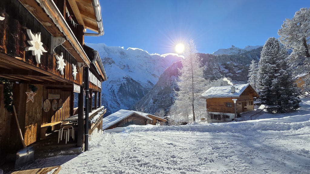 Hostel entrance and snowy alpine village in sunshine